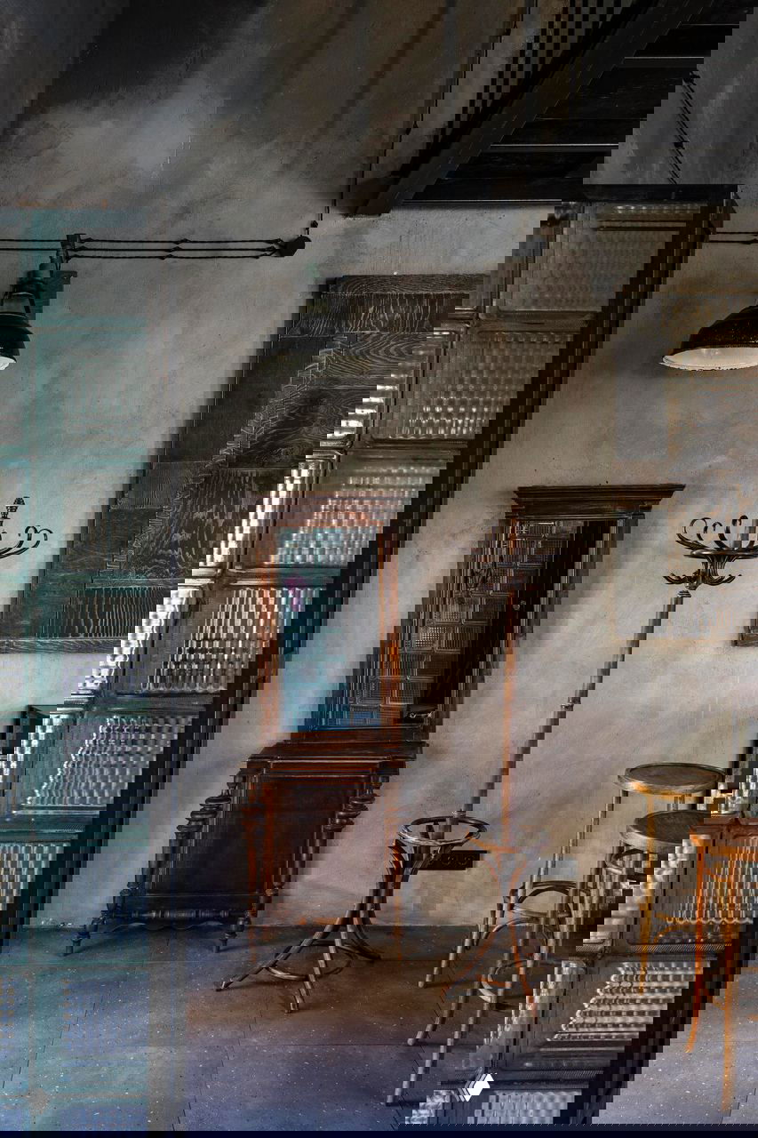 Вешалка, зеркало в деревянной раме и детали мебели на фоне серой фактурной стены — мелкие архитектурные акценты в интерьере кафе «Ровесники», фото Кирилла Овчинникова.