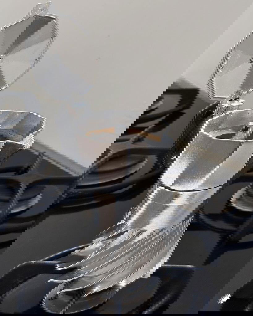 Turbo Moka на газовой плите в процессе приготовления: открыт верхний отсек, видна фильтр-камерa, сочетание классической эксплуатации и новой формы.