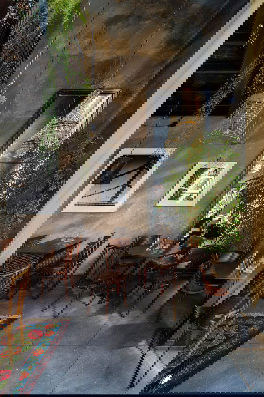 Общий план зала с высокими стенами, картинами в рамках, люстрами и расстановкой столов и стульев — атмосфера кафе «Ровесники» в Красной Поляне, фото Кирилла Овчинникова.