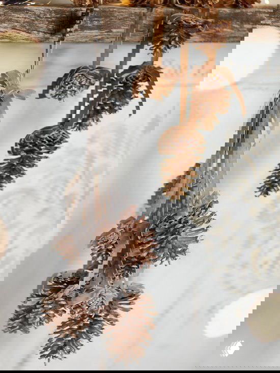 Подвесная гирлянда из нескольких окрашенных и натуральных шишек, перевязанных лентой — идея для простых самодельных подвесок и украшений интерьера.