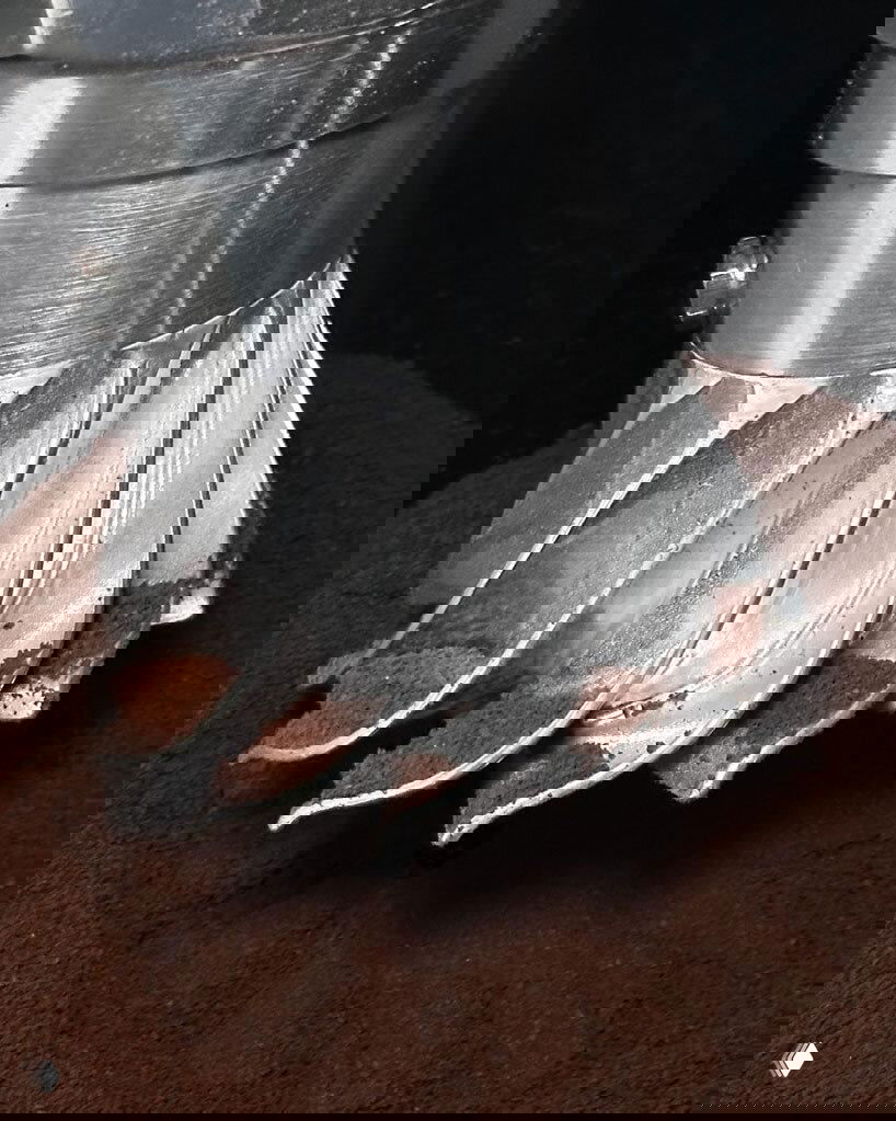 Макрофотография турбинной спирали Turbo Moka с частицами молотого кофе, акцент на литье алюминия и геометрии лопастей основания.