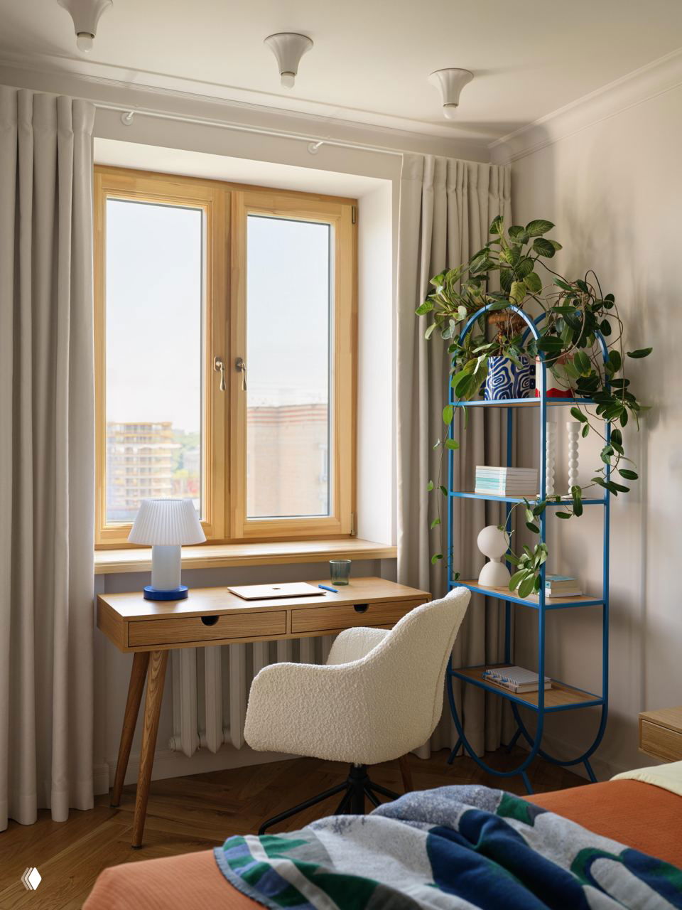 Рабочая зона у окна: деревянный стол, настольная лампа, мягкое кресло и синяя металлическая полка с декоративными растениями на светлом фоне.
