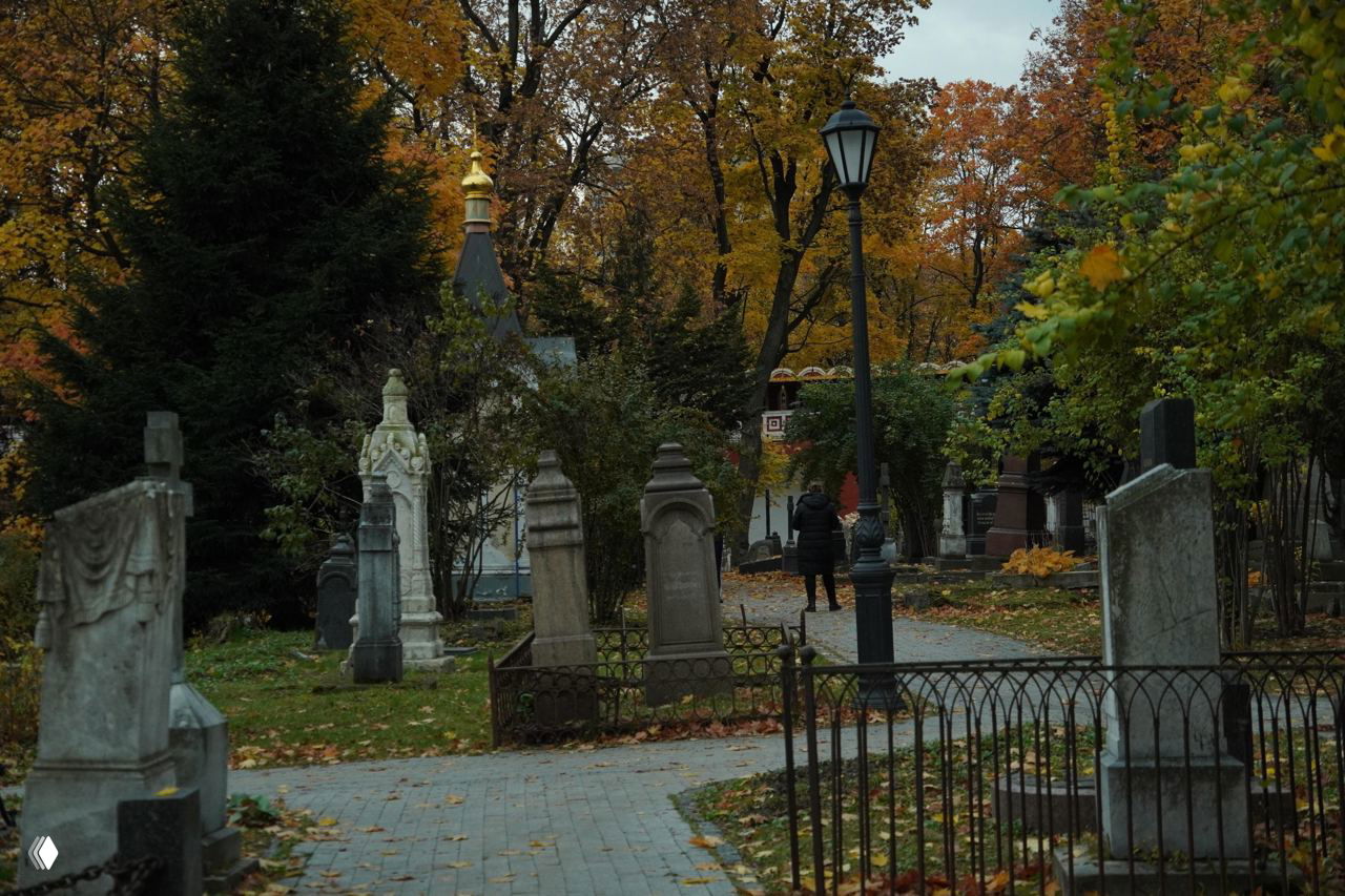 Дорожка между надгробиями и часовнями Донского монастыря, фонари и золотой купол виднеются среди осенних деревьев