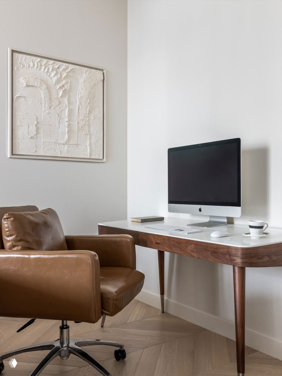Рабочее место с деревянным столом и большим монитором, рядом кожаное кресло — уютный уголок для работы в общей семейной среде квартиры.