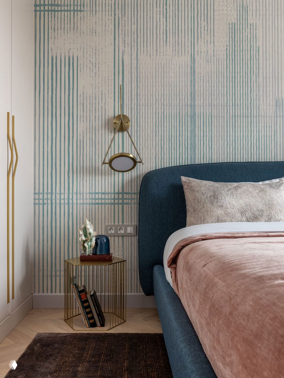 Спальня с синим изголовьем и мягким текстилем, тонкая прикроватная тумбочка из металла и журнальный столик в подборе цветов — элегантный дизайн спальни.