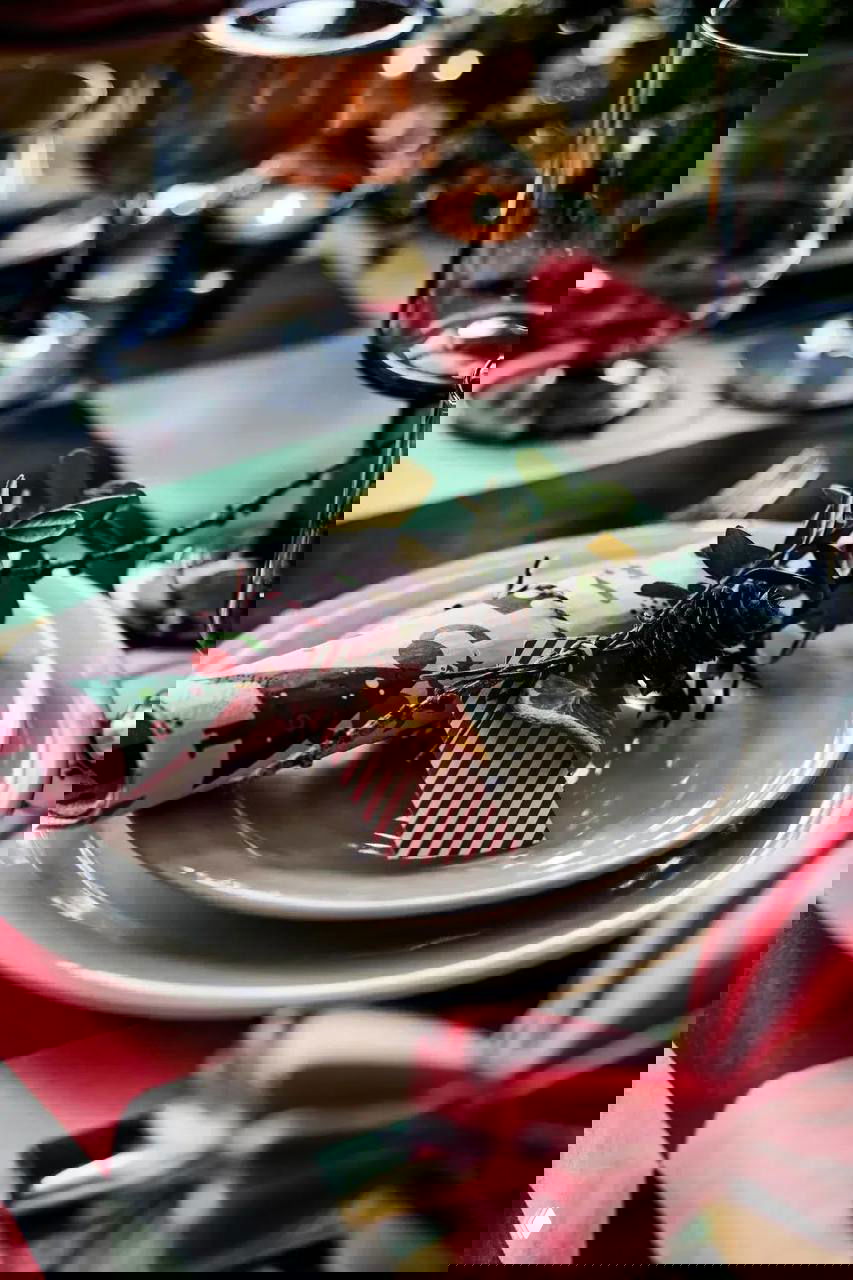 Детали праздничного стола: тарелка с декоративной веточкой, маленький подарочный ярлык и аккуратная тканевая салфетка на клетчатой скатерти