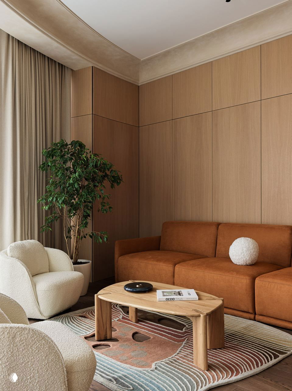 Гостиная с коричневым диваном, белыми мягкими креслами и низким деревянным столом; текстурный ковер и зелёное растение у окна создают тёплую обстановку.