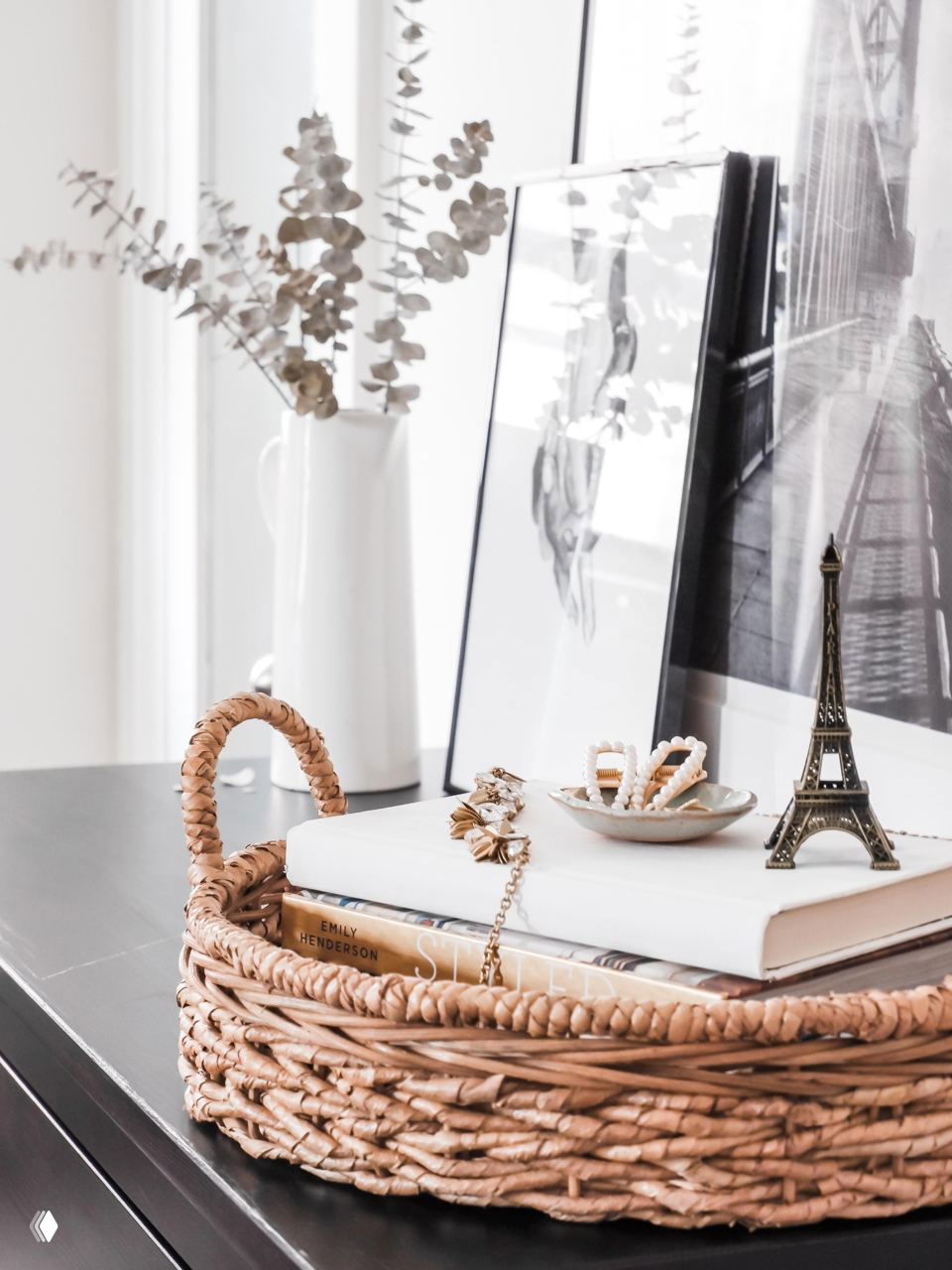Плетёный поднос с книгами, украшениями и миниатюрами на столе — стильный способ собрать мелочи и декор в одном месте.