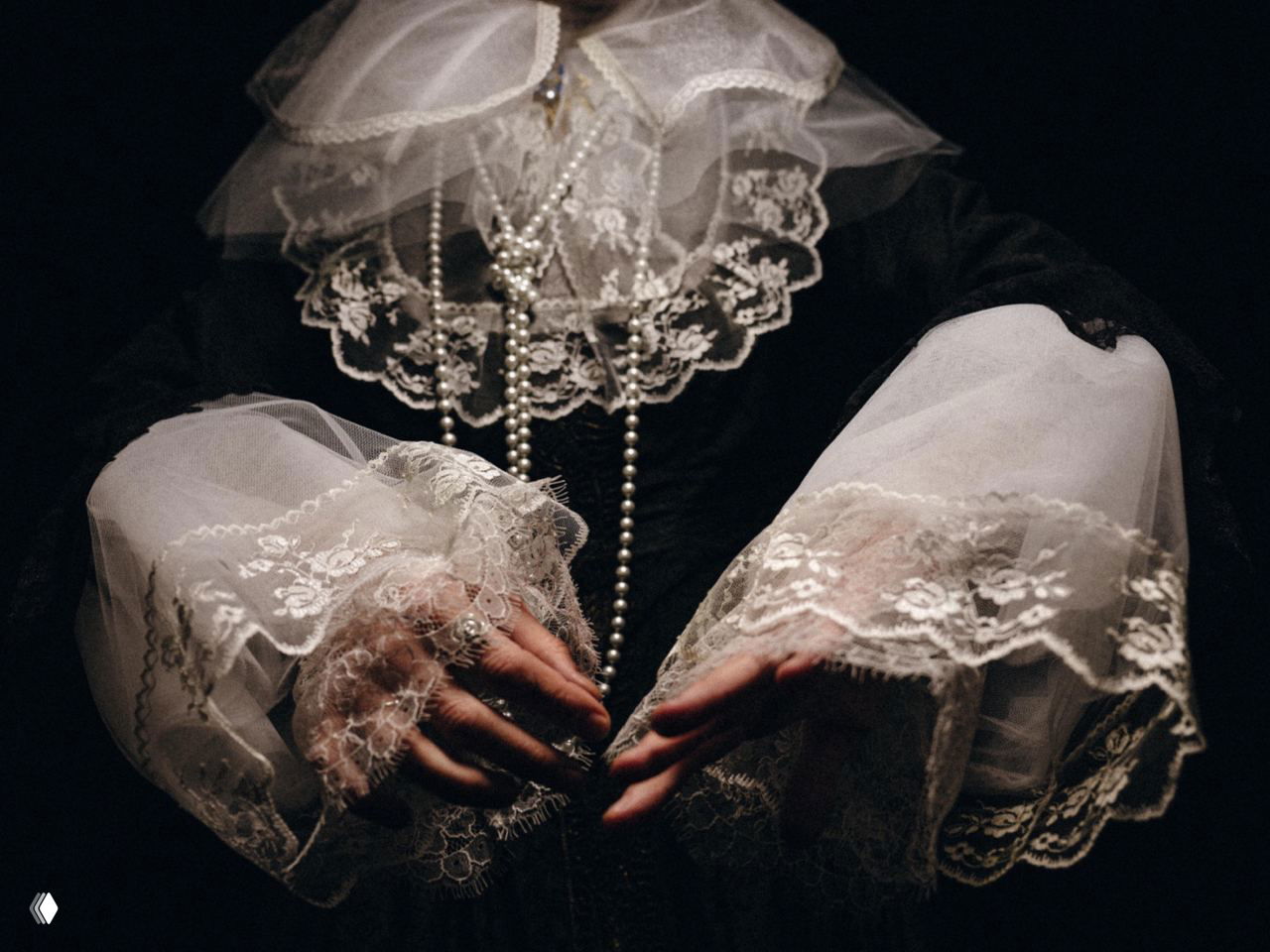 Фрагмент барочного костюма: кружевные манжеты и нити жемчуга на руках исполнителя, подчёркивающие исторический образ перформанса.