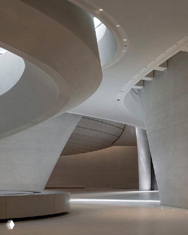 Интерьер музея: мягкие скруглённые бетонные формы атриума, чистые поверхности и рассеянный свет создают сдержанную современную атмосферу просветительского пространства.