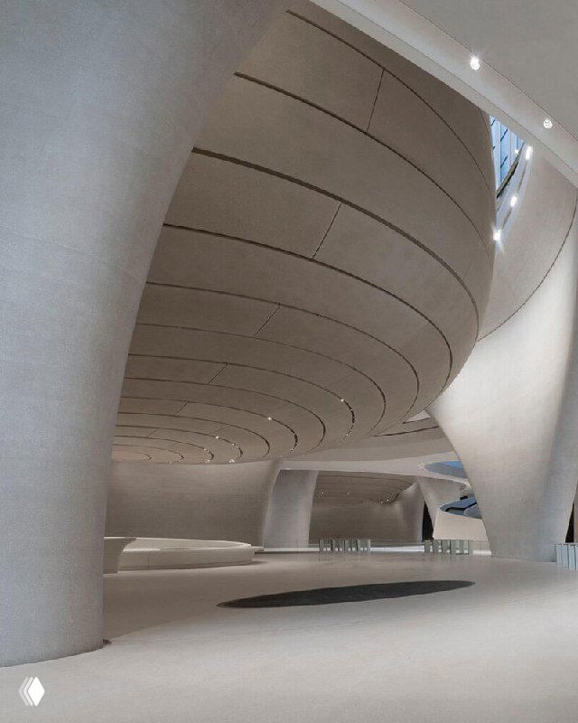 Объёмный зал с массивными монолитными колоннами и обтекаемыми линиями потолка; акцент на минималистичных формах и плавной геометрии интерьера музея.