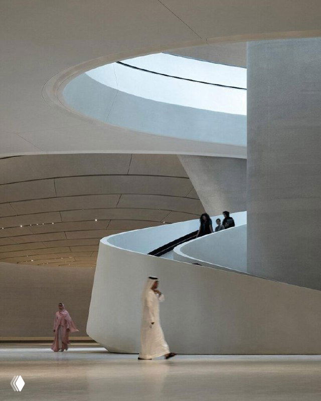 Панорамный вид галереи музея с спиралевидными элементами и гладкими поверхностями пола и стен; простор для экспозиций и движение посетителей в светлом пространстве.