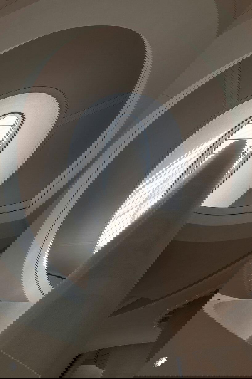 Овальное световое окно и эскалатор в атриуме Национального музея; люди в традиционной одежде дают представление о масштабе и общественном контексте интерьера.