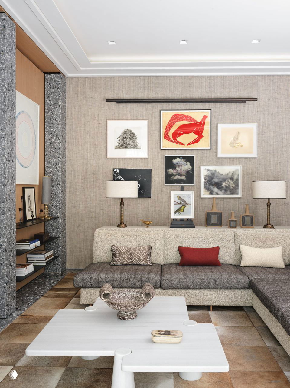 Гостиная с низким угловым диваном и галерейной стеной: несколько рамок с графикой и яркой центральной красной работой.