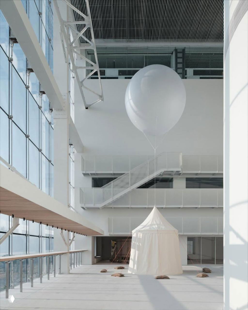 Светлый атриум Power Station of Art: белая палатка‑инсталляция и большой воздушный шар на фоне лестниц и панорамных окон; проект Chanel.