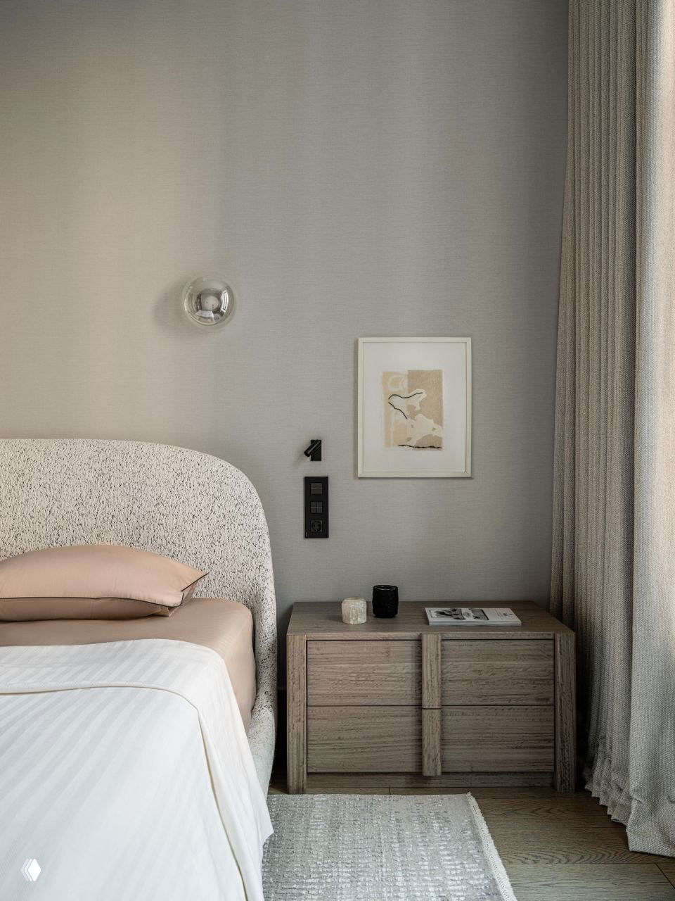 Фрагмент спальни: изогнутое текстильное изголовье, деревянная тумбочка и нейтральные текстуры на стенах и шторах.