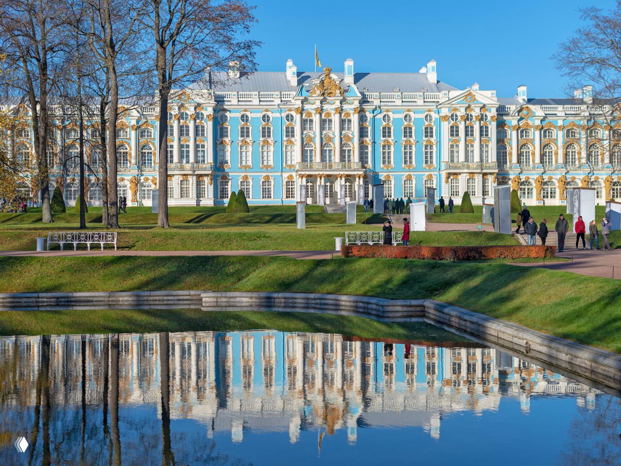 Екатерининский дворец в Царском Селе: барочный голубой фасад с золотой лепниной и его отражение в спокойном парковом пруду.