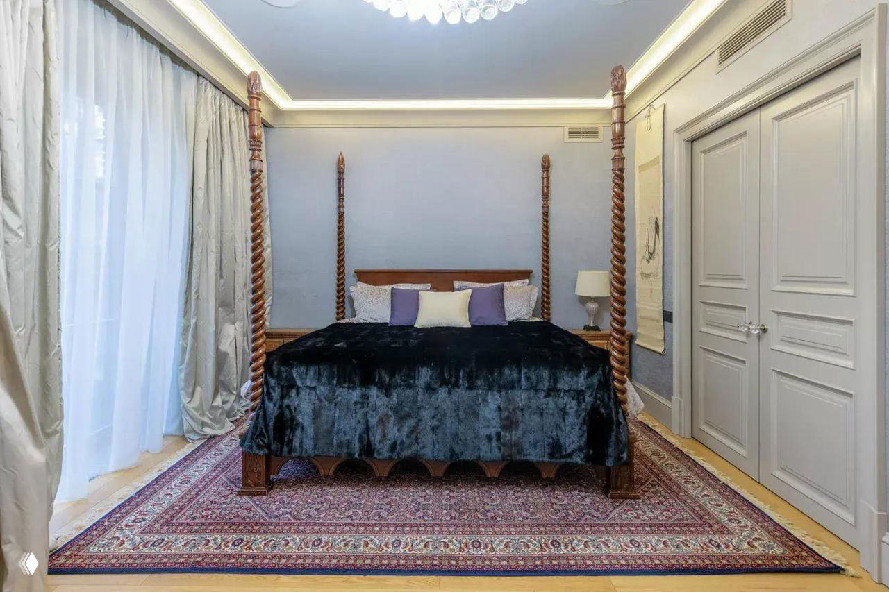 Спальня с четырёхстолбовой кроватью на ковре, тяжёлыми шторами и классическим оформлением стен — приватная зона на втором этаже особняка.