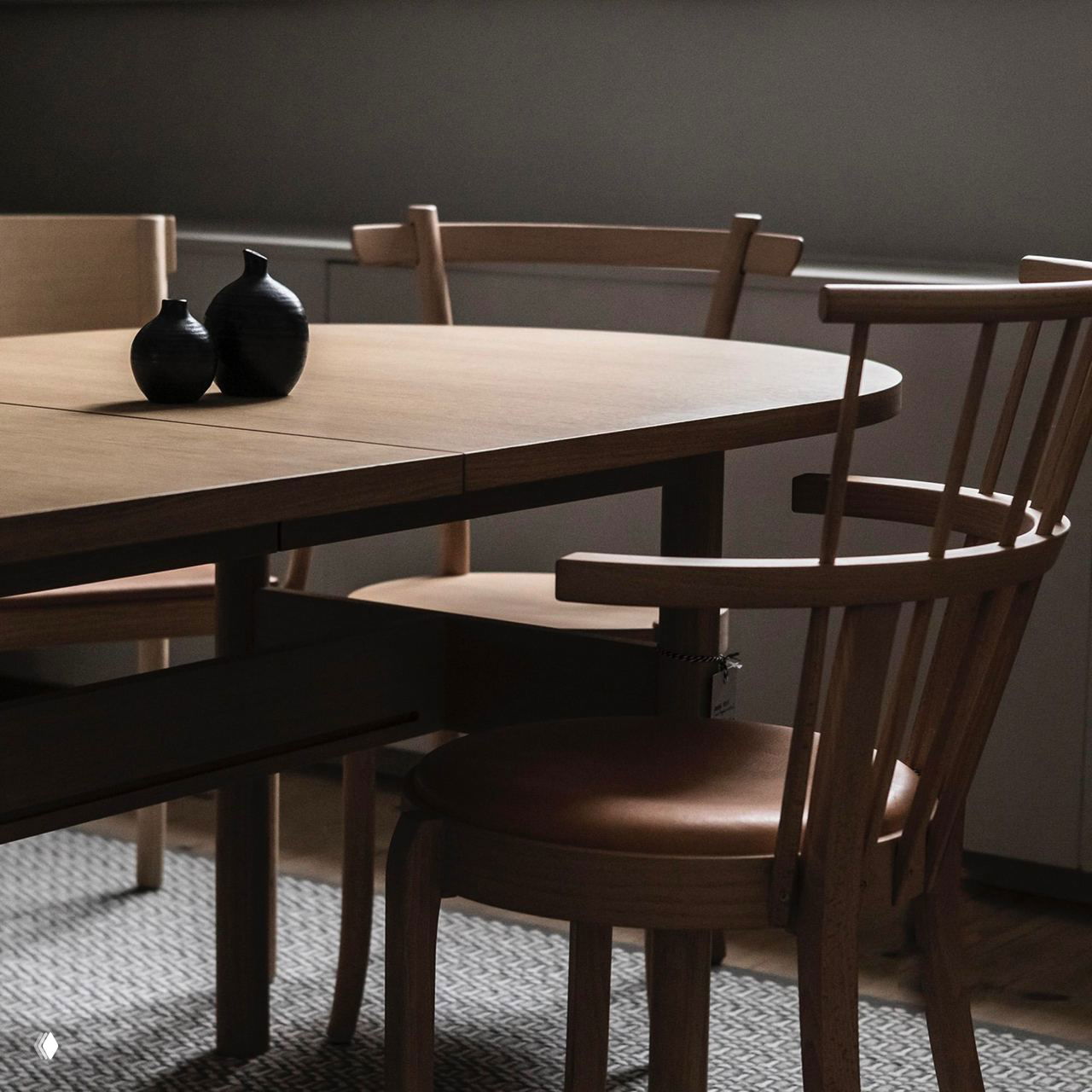 Крупный план деревянного обеденного стола и стула в естественном освещении, демонстрирующий текстуру дерева и простые чистые формы шведской мебели.