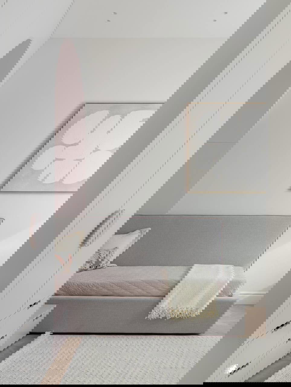 Рабочее место с белым креслом на колесиках, светлым деревянным столом и яркой оранжевой лампой как акцент в нейтральной комнате.