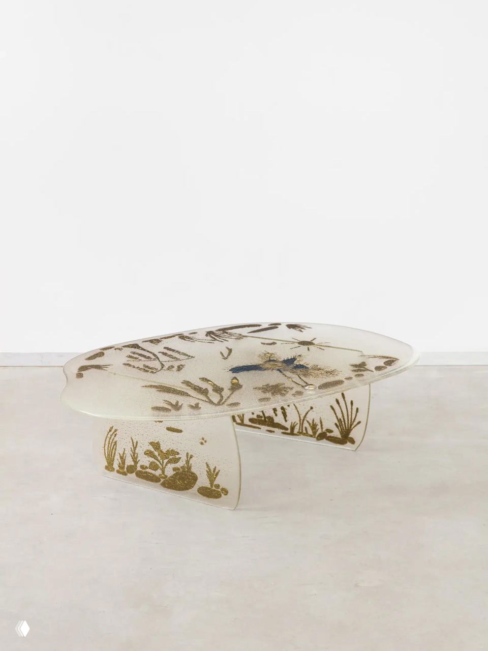 Прозрачный стол со вкраплениями и растительными узорами, похожий на отлитый из расплавленного стекла предмет, экспонат выставки дизайна в Париже.