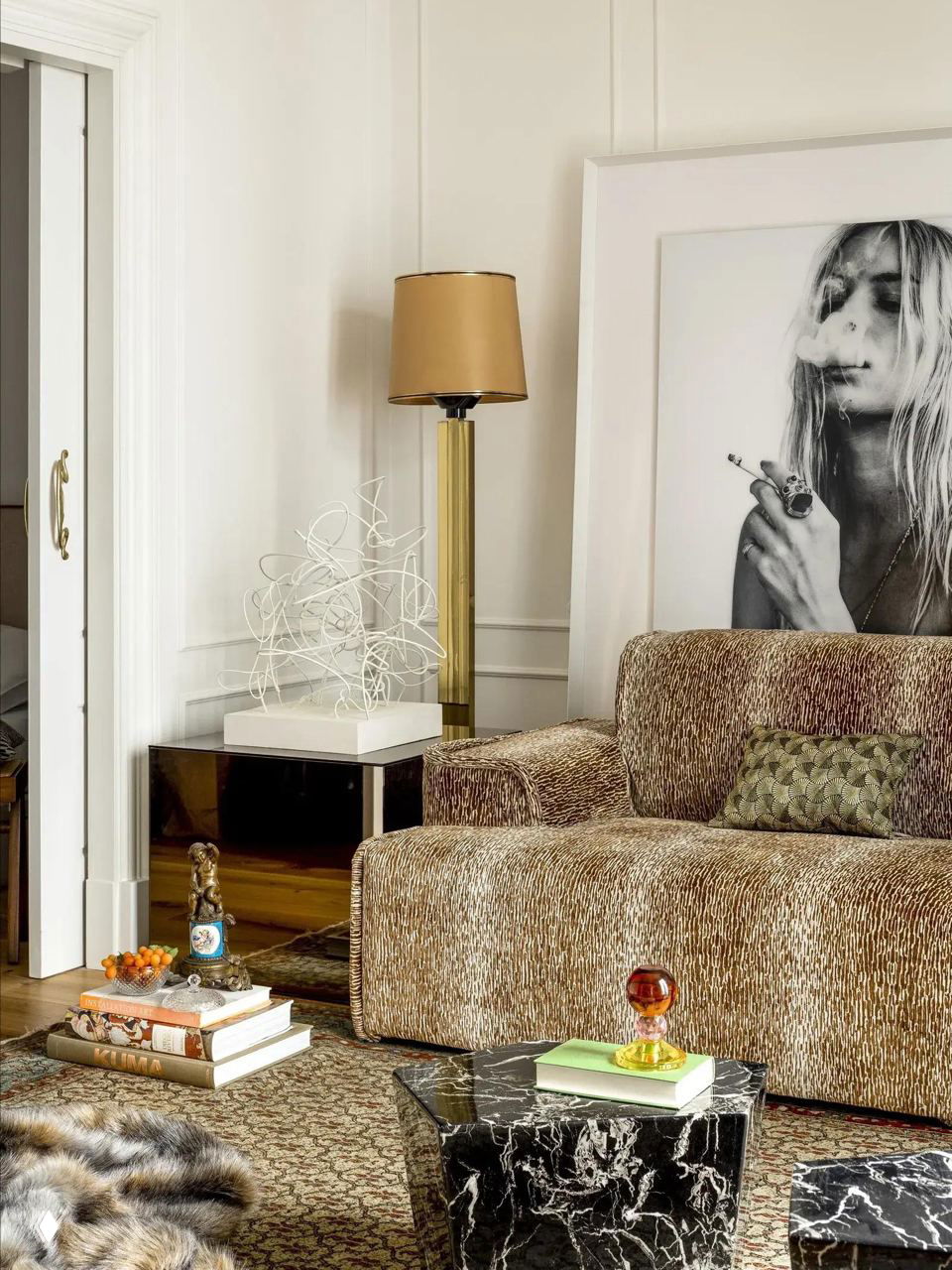 Гостиная с текстурным диваном, высоким торшером и большой чёрно‑белой фотографией над мебелью — сочетание винтажа и современности в оформлении.