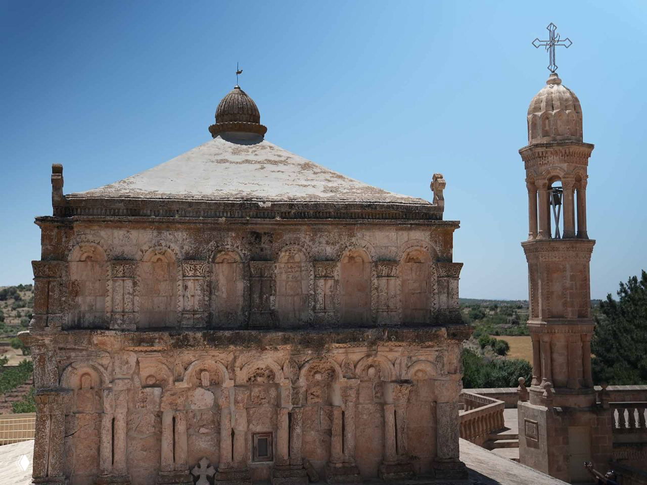 Фрагмент фасада древней церковной постройки IV–V веков в Анытлы: резные арки, рельефы и купол с крестом на верхушке.