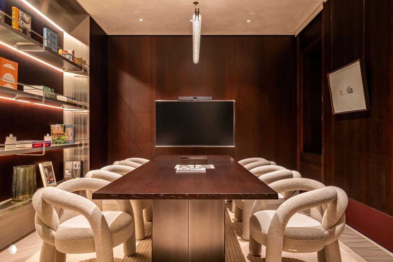 Переговорная комната с длинным столом, обитыми стульями с морскими узлами и встроенными книжными полками на стене.