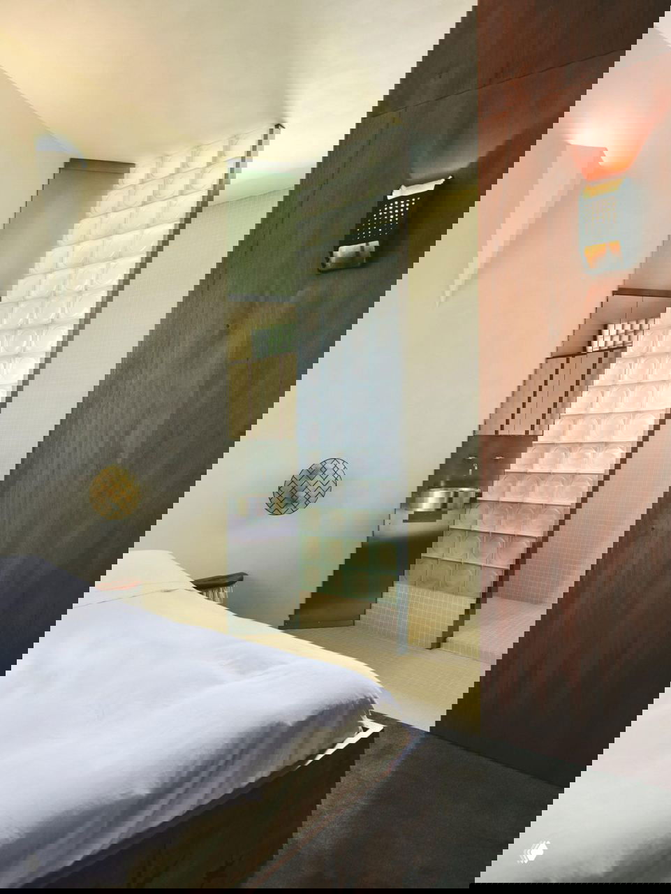 Ближний план зоны умывальника: круглая металлическая раковина и панель из стеклоблоков, минималистичная встроенная мебель.