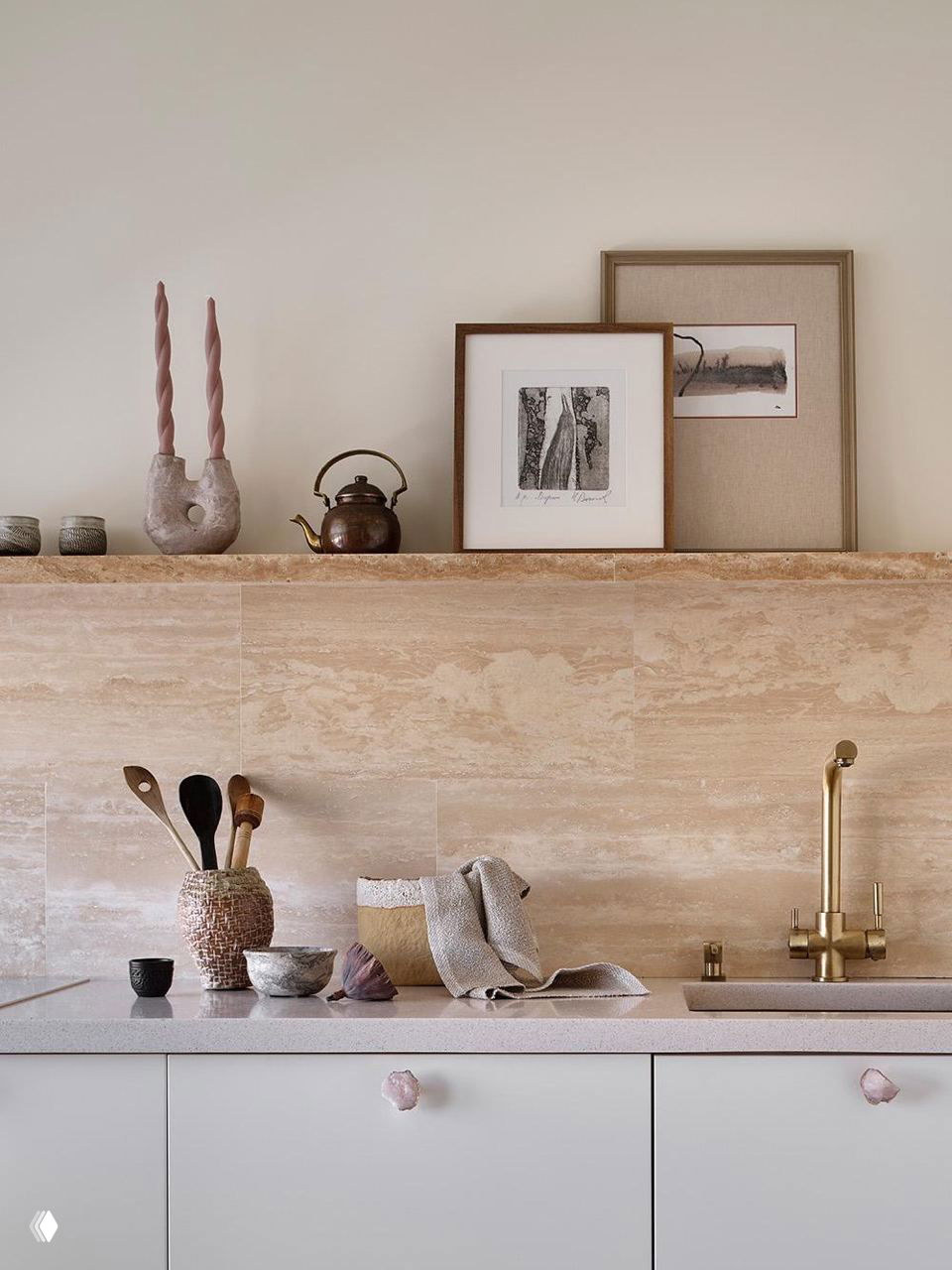 Пастельная кухня с низкими шкафами и мраморной стеной, открытая ниша над столешницей для декоративных аксессуаров вместо верхних шкафов.