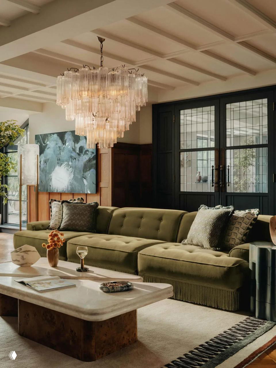 Просторная гостиная с оливковым диваном на бахроме, эффектной люстрой и каменным журнальным столом — сочетание винтажных деталей и современной роскоши.
