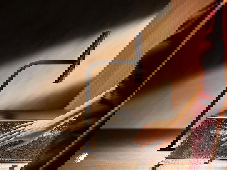 Интерьерная сцена с тёплым боковым светом: матовый смеситель и тёмная фактурная раковина, акцент на материале и форме.