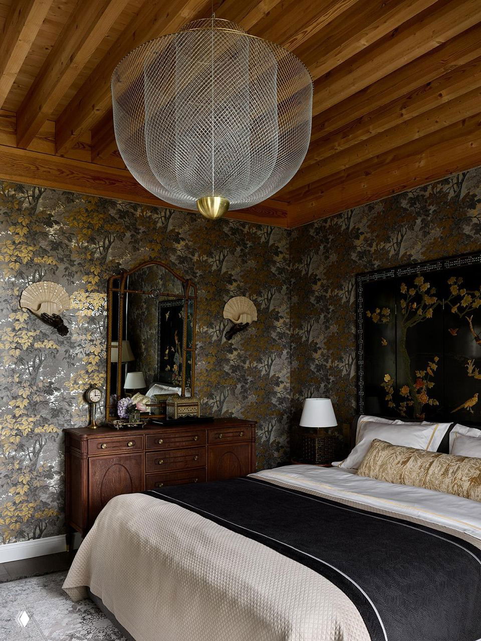 Спальня с обоями в азиатском стиле, деревянными балками, классическим комодом и мягкой кроватью с золотыми акцентами; интерьер в Подмосковье.