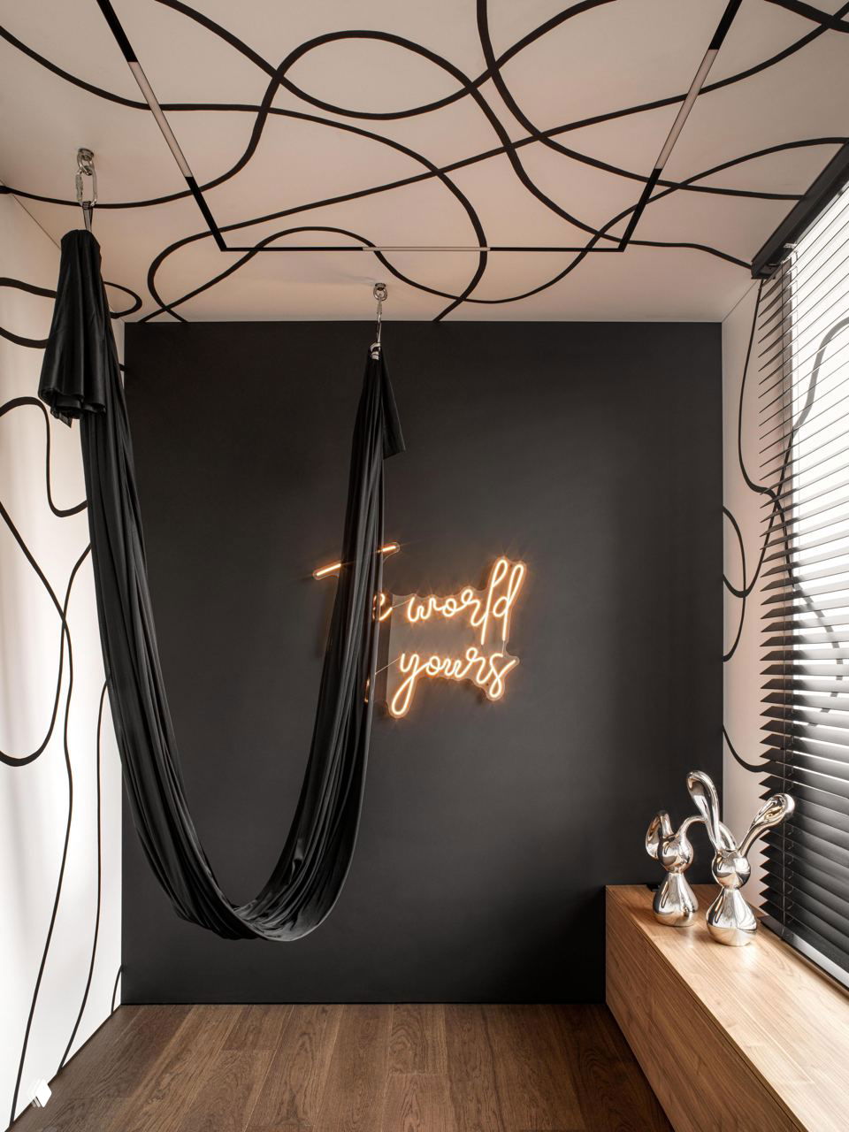 Комната для йоги или релакса: подвесное полотно/гамак на фоне графичных черных линий и неонной надписи, контрастный монохромный акцент.