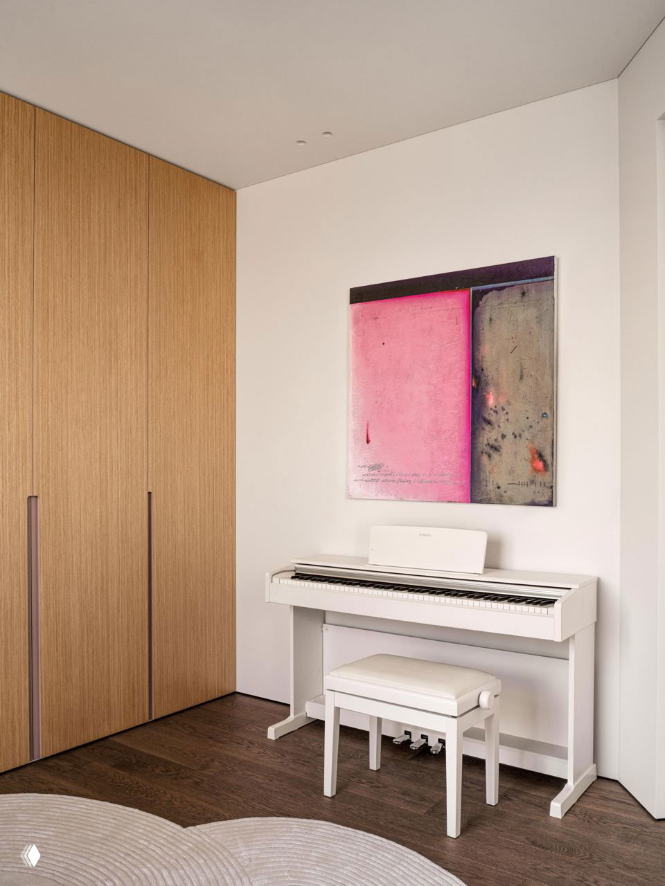 Пианино в светлой нише, пастельная картина над инструментом и паркетный пол — зона для творчества и музыки в квартире семьи из трех человек.