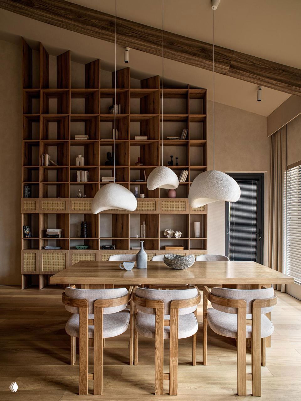 Столовая с большим деревянным столом и четырьмя стульями на фоне модульного деревянного стеллажа; мягкая тёплая палитра в стиле тихой роскоши.