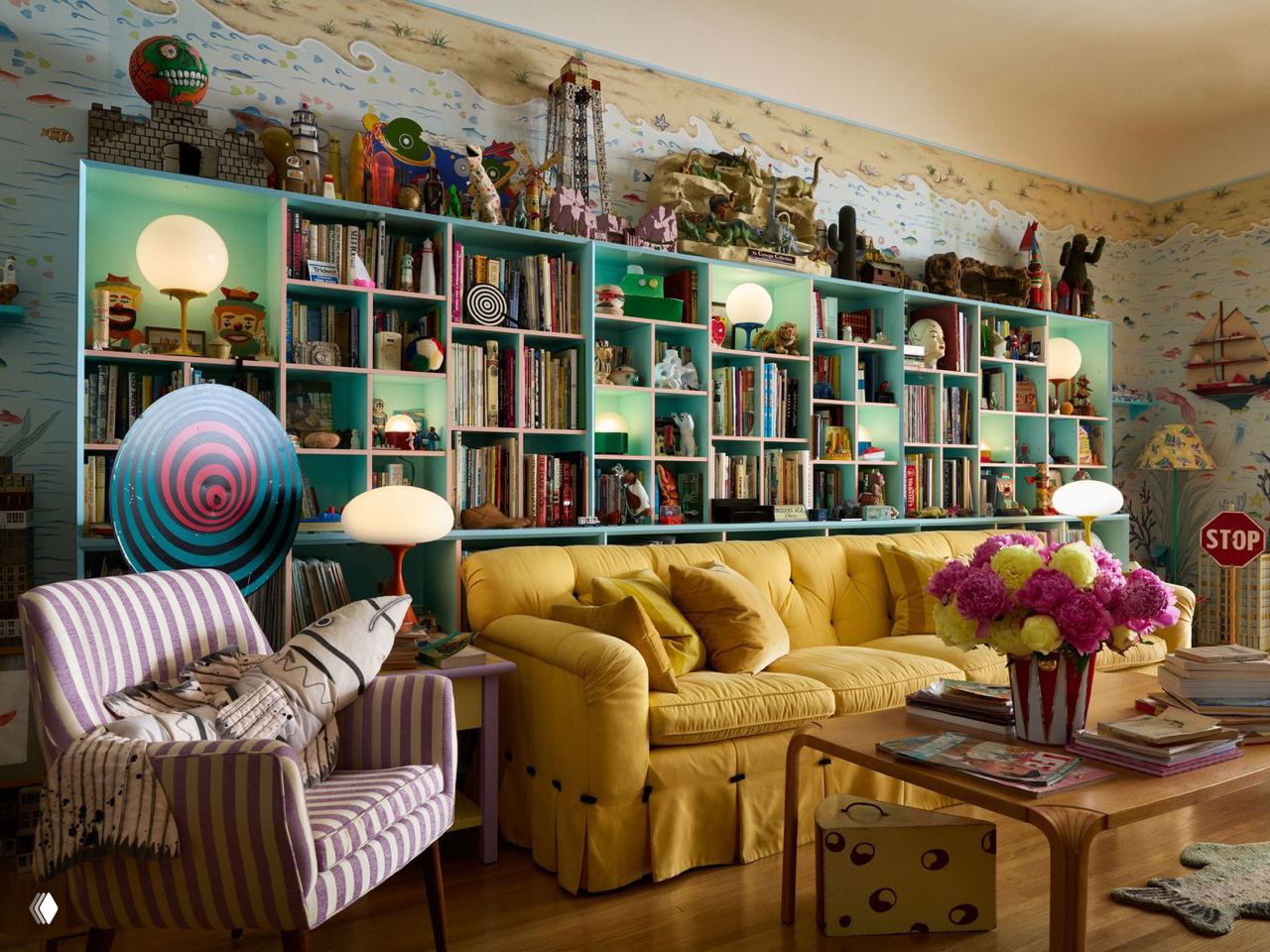 Яркая гостиная с желтым диваном, бирюзовыми стеллажами, множеством игрушек и книг — насыщенный максималистский интерьер в бруклинском доме.