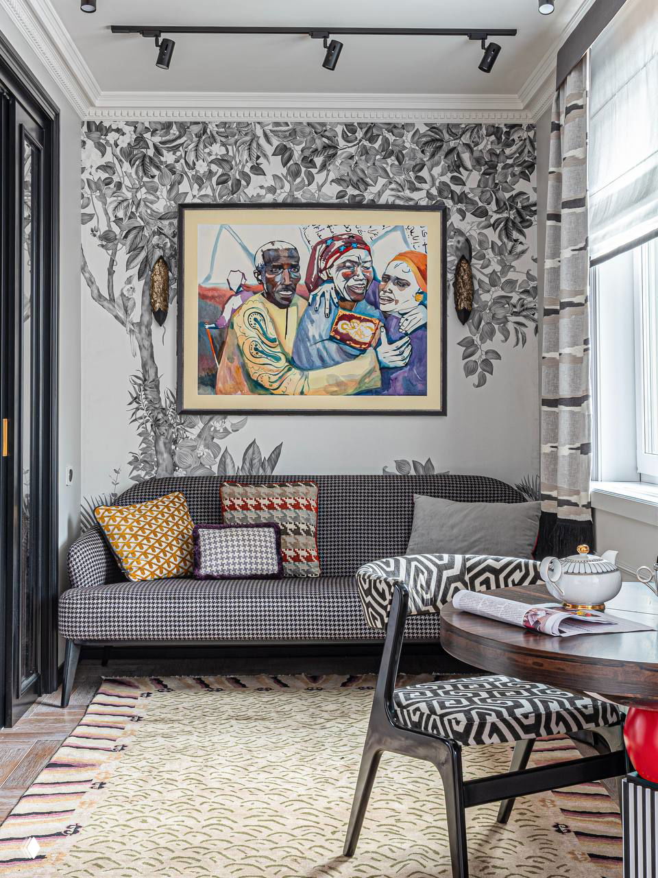 Уютная гостиная со светло-серой мебелью и монохромной растительной росписью на акцентной стене, яркая картина в раме над диваном.