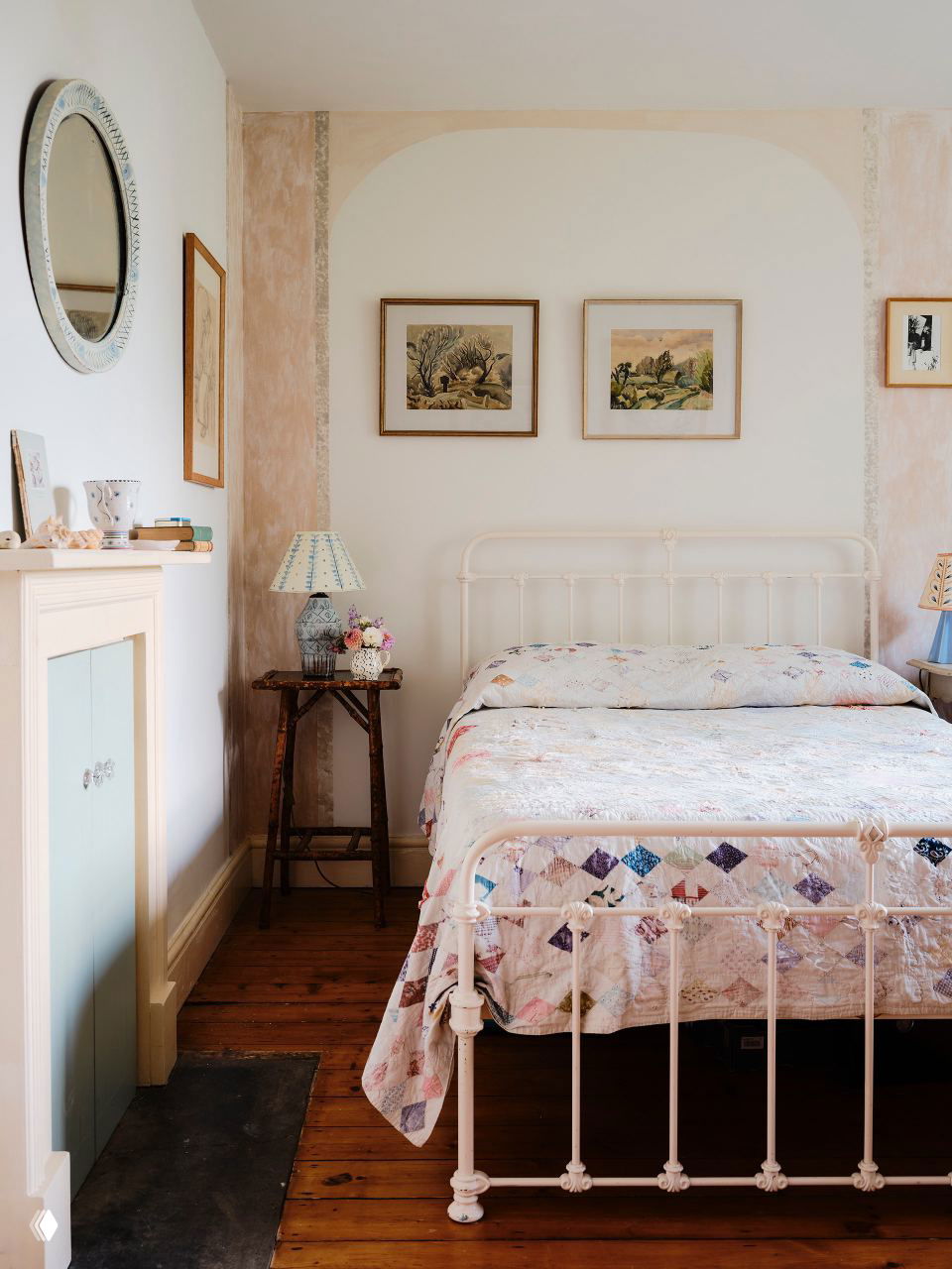 Ещё одна спальня с белой железной кроватью и лоскутным покрывалом, картинами над изголовьем и деревянным полом в классическом стиле.