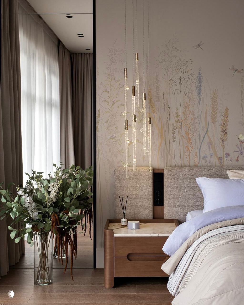 Спальня с тонкой растительной росписью на стене, прикроватной тумбой из дерева и нежными подвесными светильниками вдоль изголовья.