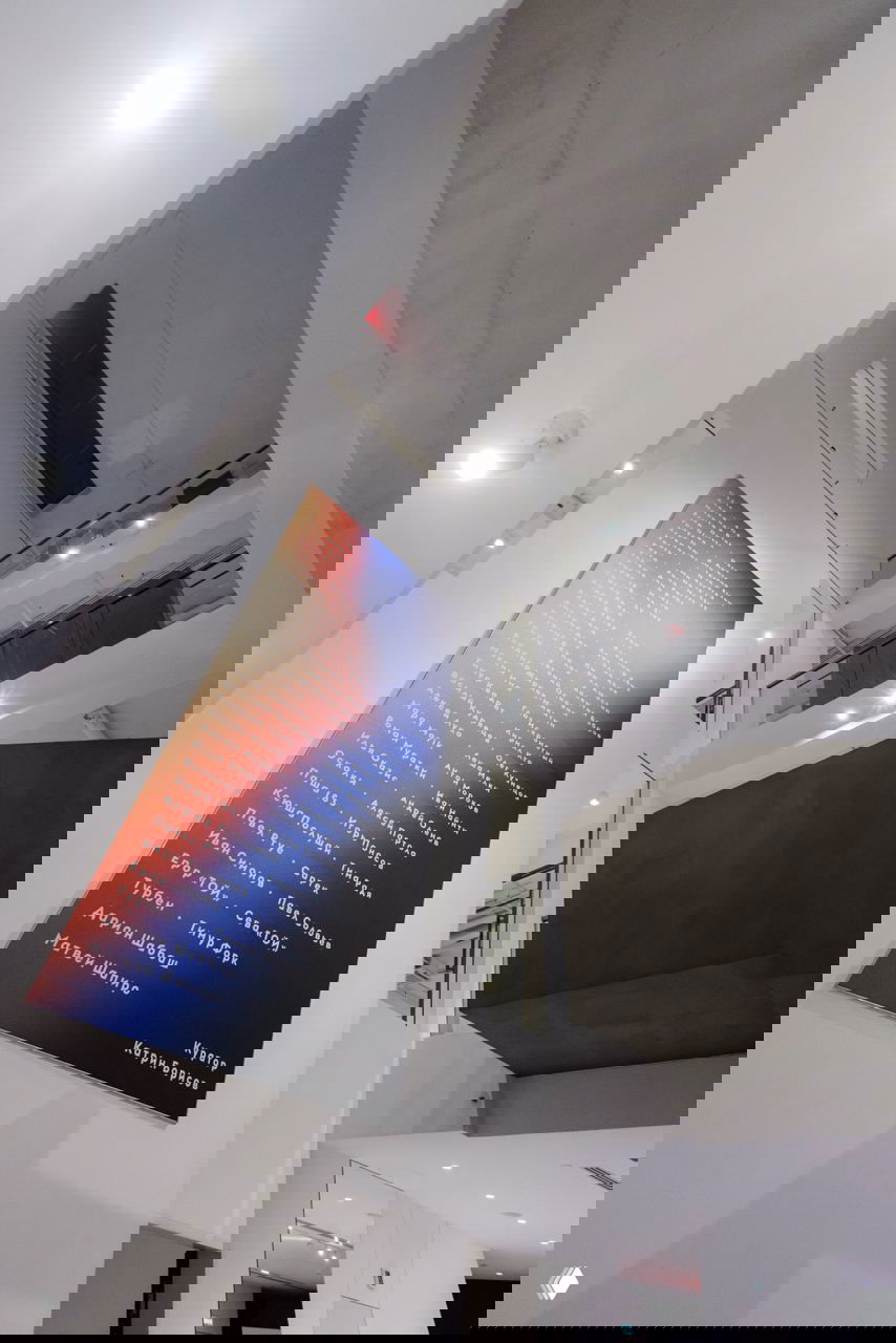 Интерьер белого холла Фонда Ruarts с большим вертикальным баннером выставки «5 углов», вид на балконы и галерейное освещение.