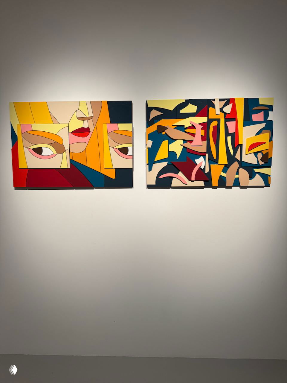 Две небольшие яркие модернистские картины на белой стене: геометризированные лица и абстрактные фрагменты в насыщенных цветах.