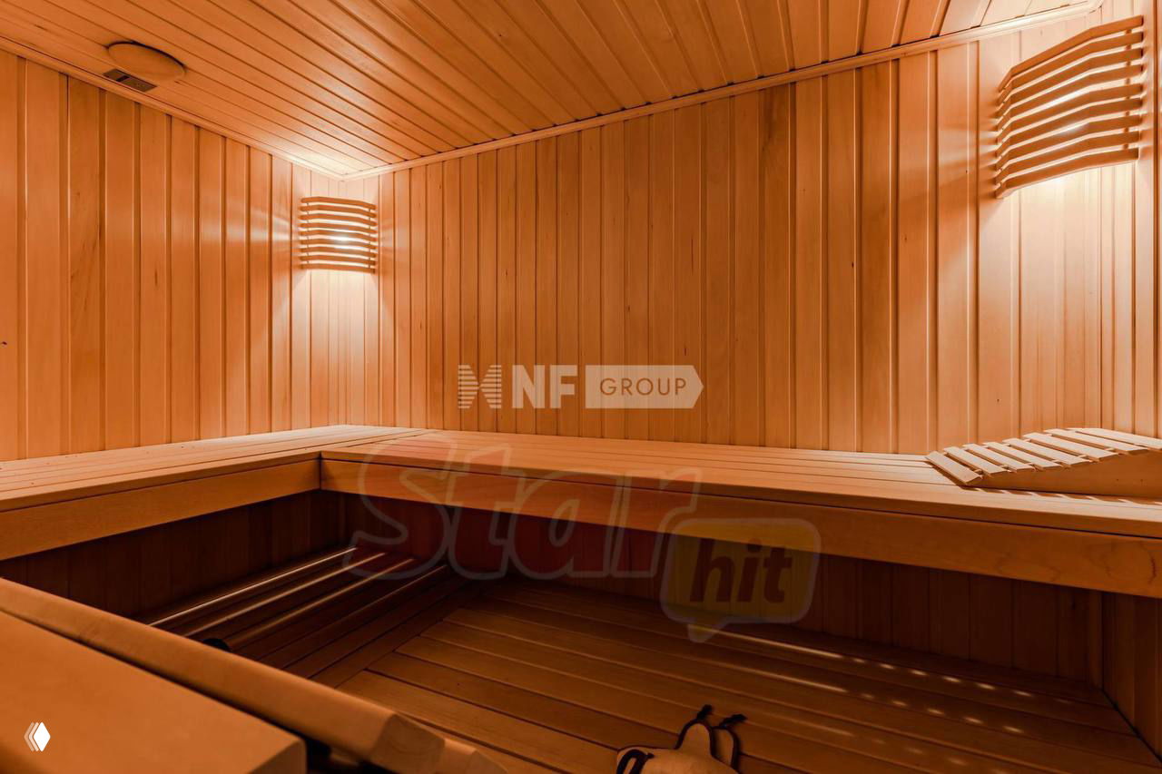 Тёплая отделка сауны в доме: панели из светлого дерева, лавки и приглушённое освещение для релаксации после бассейна или тренировки.