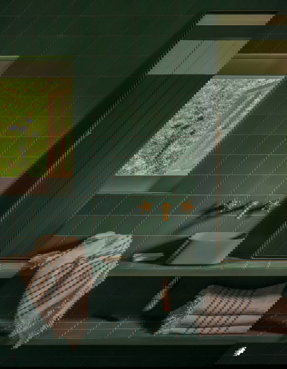 Тёмно-зелёная ванная комната с плиткой, маленьким окном, керамической раковиной и текстильными полотенцами — пример продуманной палитры и материалов в домике.