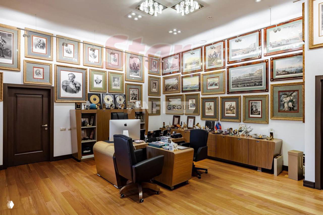 Рабочий кабинет с множеством картин и наград на стенах, письменный стол и стеллажи — интерьер, напоминающий студию или кабинет продюсера.