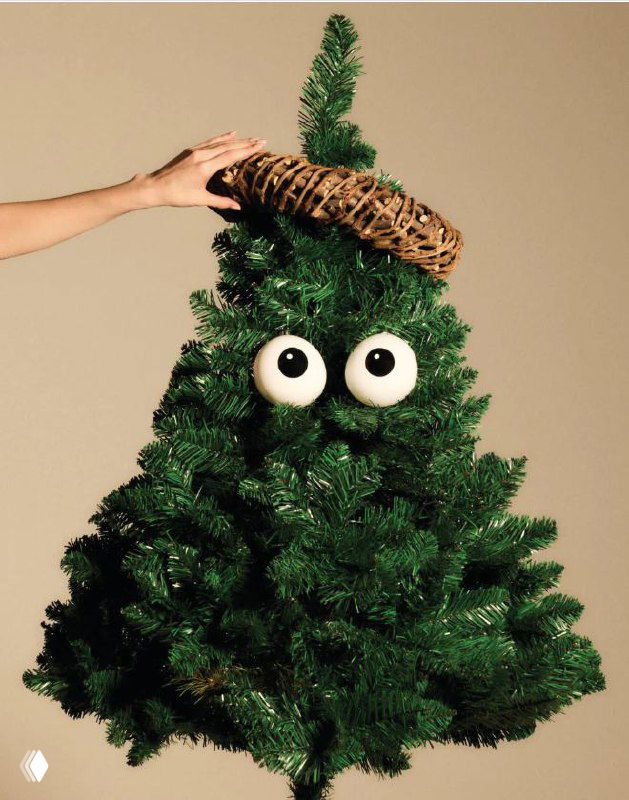 Фотография крупным планом: декоративная рождественская композиция и елочные украшения Alessi из коллекции 2025/26 на нейтральном фоне.