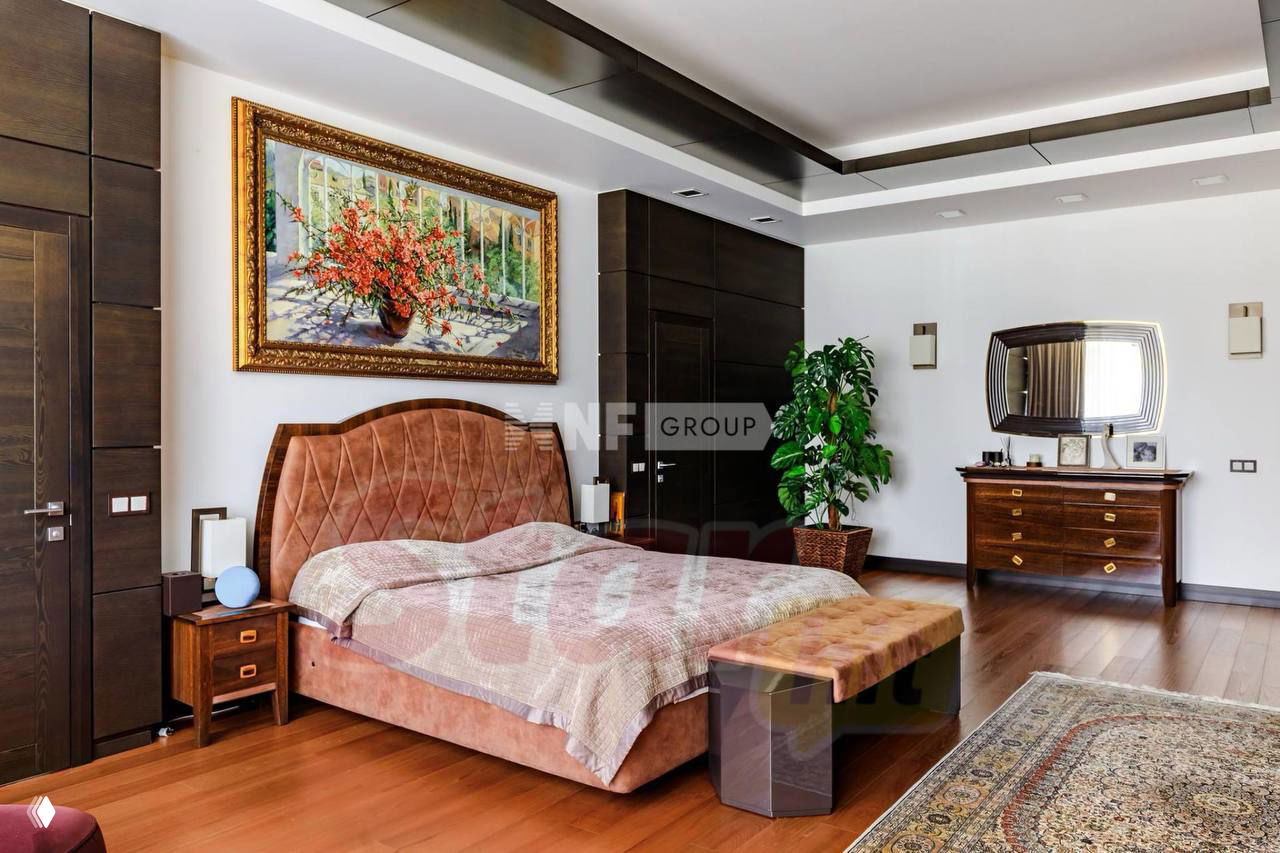 Спальня с крупной мягкой кроватью, деревянным паркетом и декоративной картиной над изголовьем — уютная персональная зона внутри дома.