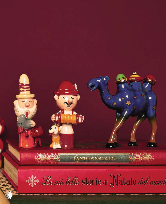 Набор керамических фигурок и декоративных персонажей Рождества на стопке подарочных изданий — игрушки и фигурки из рождественской линейки Alessi.