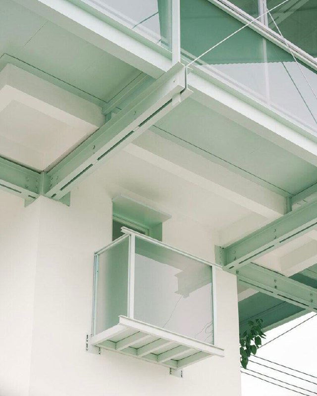 Крупный план на стальные балочные соединения и маленький балкон с прозрачным ограждением, выполненные в светло-зелёной палитре реставрации башни.