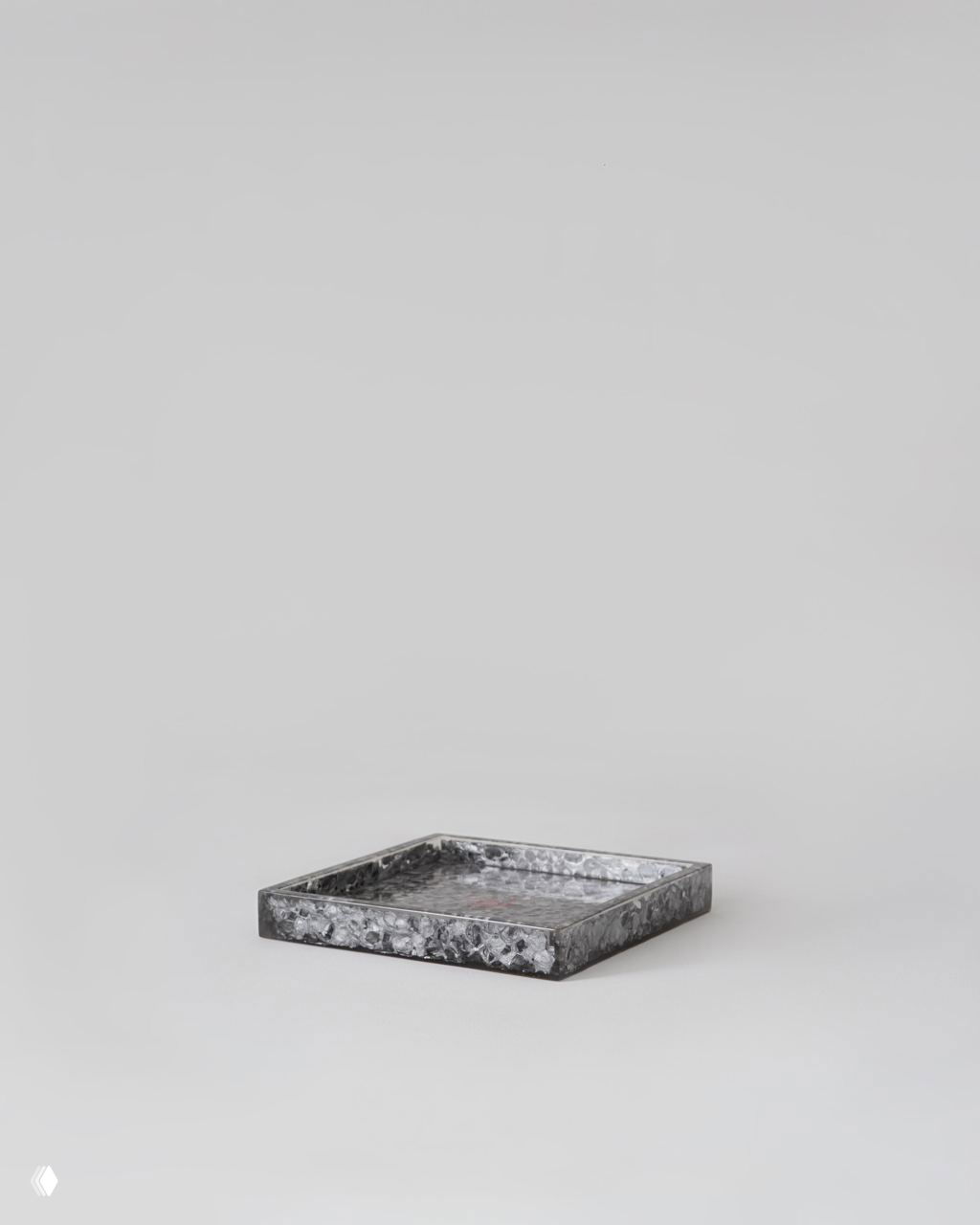 Плоский поднос или тарелка с фактурной поверхностью из материала, похожего на смолу или металл, показанный отдельно — часть набора элементов коллекции Tons.